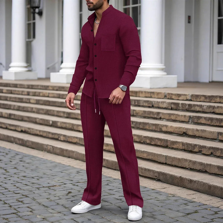 Man wearing a burgundy textured two-piece set with relaxed fit, long sleeves, and white sneakers