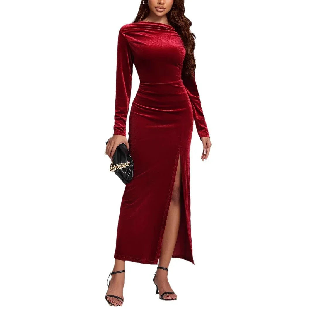 Woman wearing a fitted burgundy velvet long-sleeve maxi dress with side slit