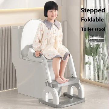 Child wearing loose cream nightgown with grey collar and cuffs, seated on toilet with foldable toilet training step stool in modern bathroom.