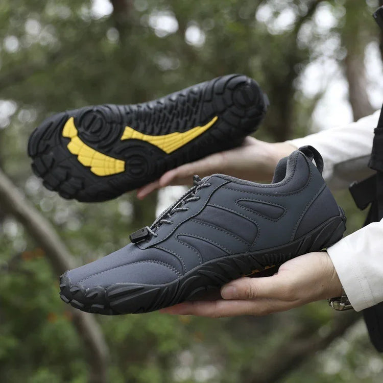 Dark grey low-top athletic sneakers with rugged black and yellow soles, outdoor setting