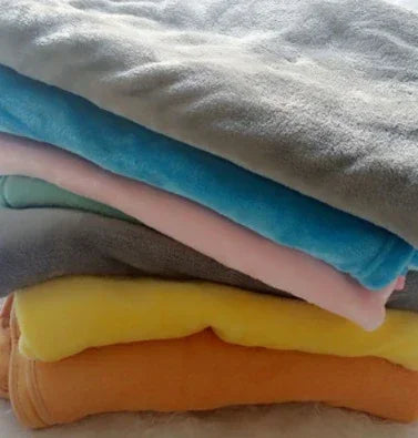 Stack of soft fleece blankets in gray, blue, pink, yellow, and orange, folded neatly.