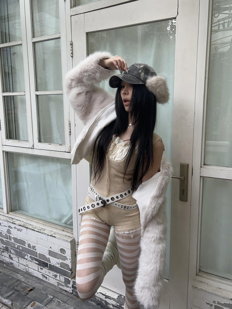 Woman in beige ribbed romper, sheer striped tights, faux fur jacket, and camo cap