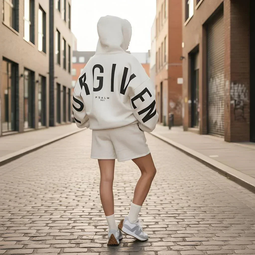 Person wearing oversized white hoodie with bold black text and matching shorts, streetwear style