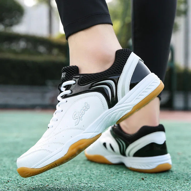 White and black athletic sneakers with mesh upper, gum soles, and sporty slim fit on outdoor court.
