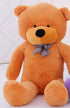 Large plush teddy bear with light brown soft fabric and checkered bow tie, seated upright