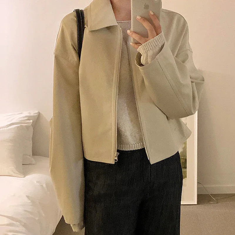 Beige zip-up jacket with a relaxed fit over a light sweater, paired with dark pants.