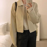 Beige zip-up jacket with a relaxed fit over a light sweater, paired with dark pants.