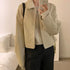 Beige zip-up jacket with a relaxed fit over a light sweater, paired with dark pants.