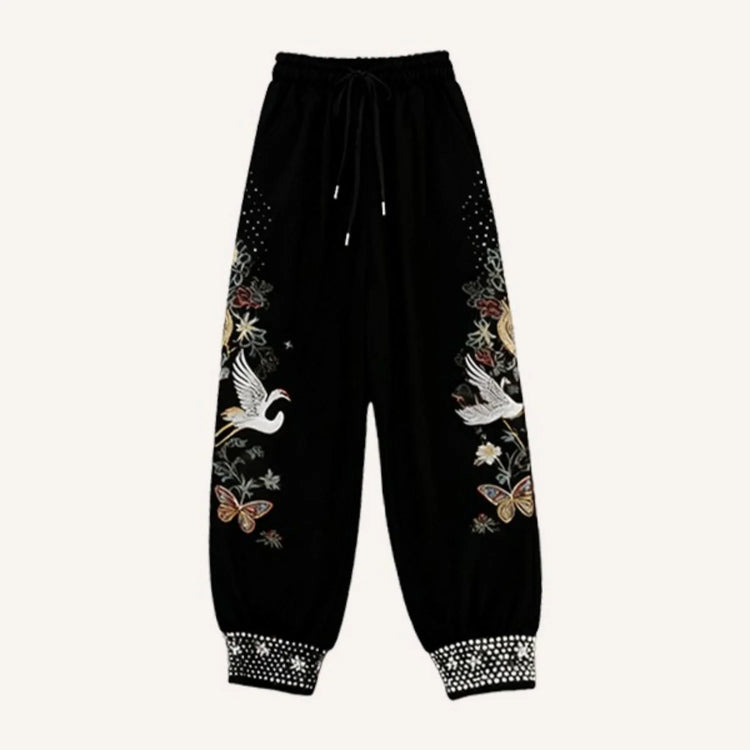 Black streetwear jogger pants with floral, butterfly, and crane embroidery, relaxed fit