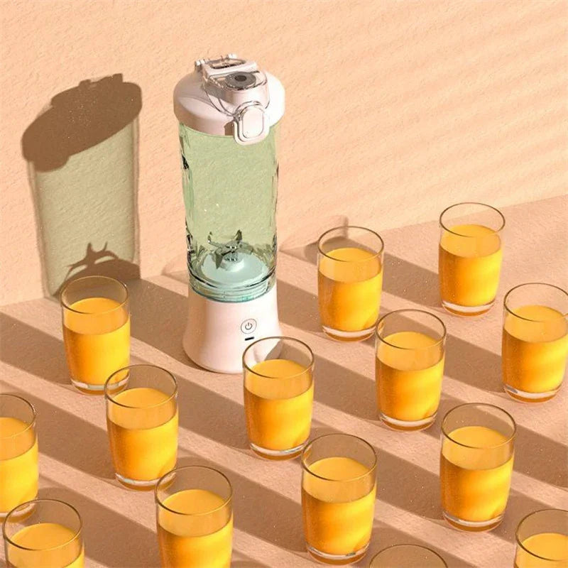 Portable blender with clear plastic jar, white base, surrounded by glasses of orange juice