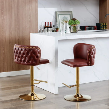 Pair of modern bar stools with brown tufted leather upholstery and gold metal base