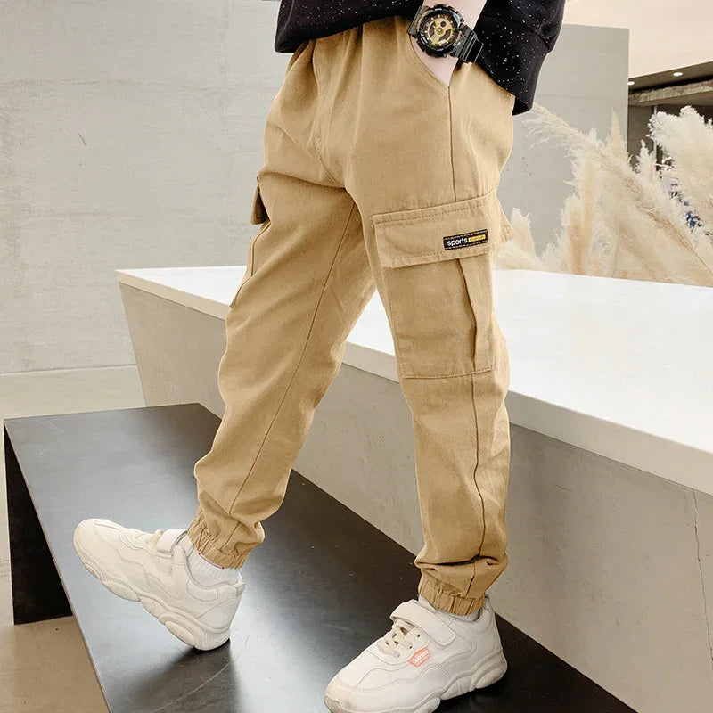 Beige cargo jogger pants with elastic cuffs, relaxed fit, paired with white sneakers