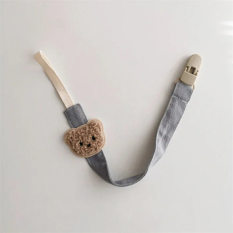 Cute neutral pacifier clip with gray fabric strap and plush bear head accent