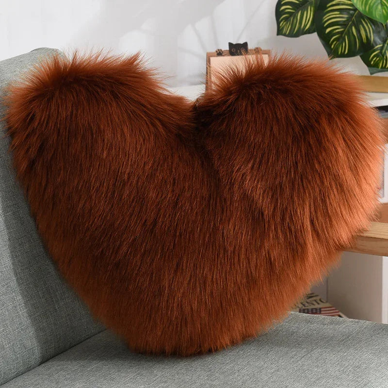 Brown faux fur heart-shaped pillow with fluffy texture on a gray sofa