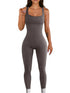 Woman wearing a fitted ribbed grey sleeveless jumpsuit, seamless design, scoop neck, bodycon style.
