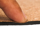 Close-up of a finger pressing a brown cork and black foam layered material, showing thickness and texture