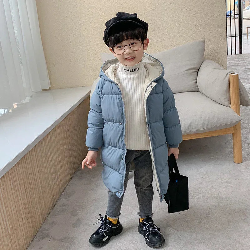 Child wearing a light blue puffer coat, white ribbed turtleneck, gray pants, and black sneakers