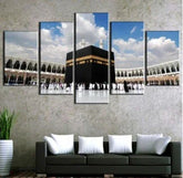 Modern wall art of Kaaba above a dark sofa with white cushions in contemporary living room