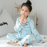Child wearing light blue striped long-sleeve pajamas with bunny print, sitting on bed