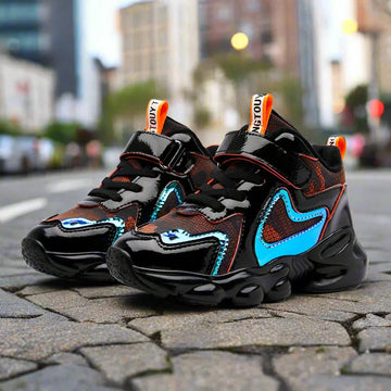 Chunky black and blue streetwear sneakers with glossy finish and mesh panels on city pavement