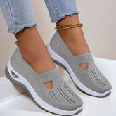Light gray slip-on sneakers with breathable knit mesh material and white soles, worn with frayed skinny jeans.