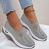 Light gray slip-on sneakers with breathable knit mesh material and white soles, worn with frayed skinny jeans.