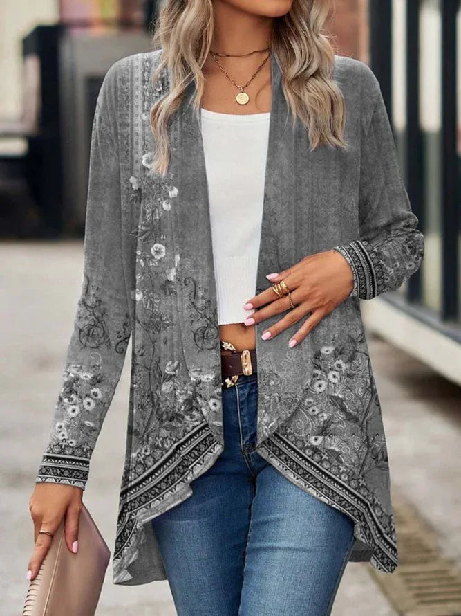 Woman wearing a gray floral patterned open-front cardigan, white crop top, and blue jeans.