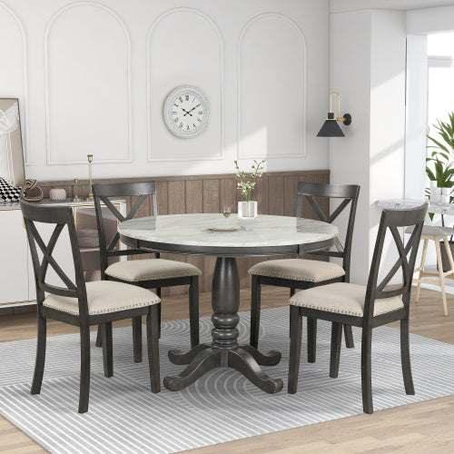 Round marble dining table with four cushioned wooden chairs in modern kitchen