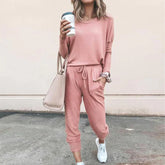 Woman wearing a pink lounge set with drawstring joggers, relaxed fit, and white sneakers