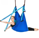 Woman in a black crop top and fitted leggings using a blue aerial yoga hammock swing