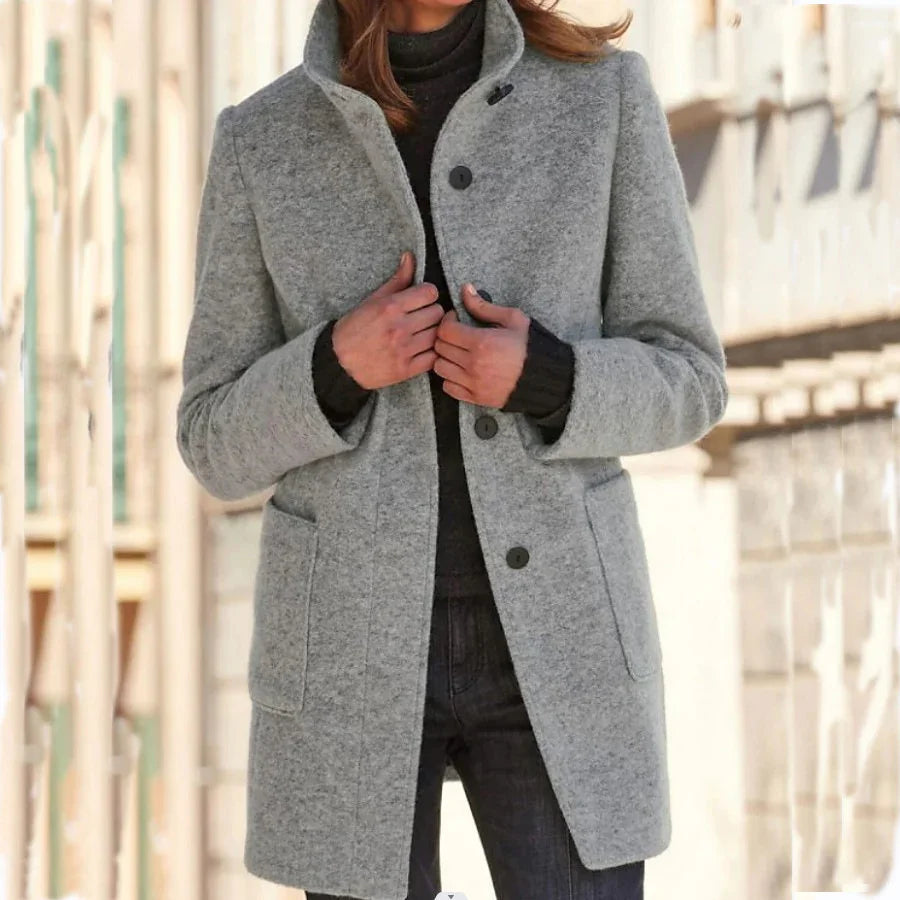 Woman wearing a light gray wool coat with button closure and relaxed fit over a black sweater