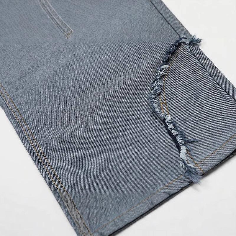 Close-up of blue denim pant leg with raw edge distressed hem, straight fit style