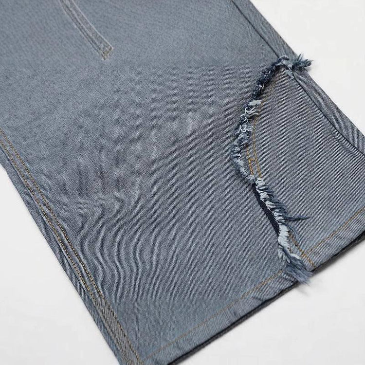 Close-up of blue denim pant leg with raw edge distressed hem, straight fit style