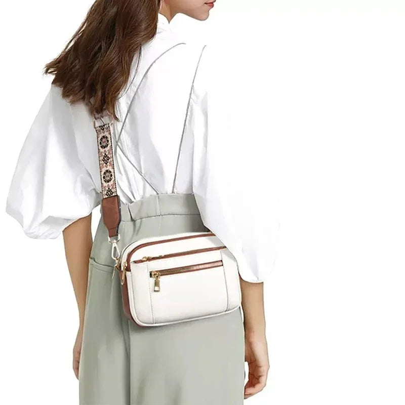 Woman wearing a white puff-sleeve blouse, high-waist pants, and a beige crossbody bag with a patterned strap.