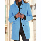 Woman wearing a light blue wool coat with black buttons, tailored fit, and front pockets