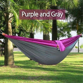 Purple and gray nylon hammock hanging between palm trees outdoors