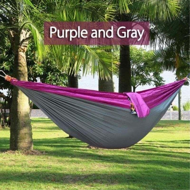 Purple and gray nylon hammock hanging between palm trees outdoors