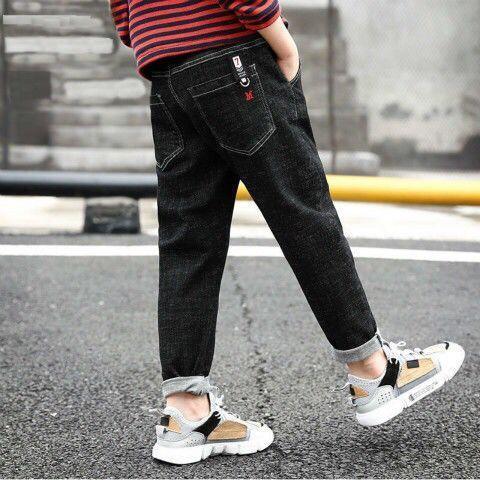 Black relaxed-fit denim jeans with rolled cuffs, red accent, paired with chunky sneakers