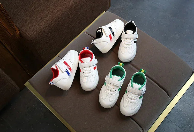 White toddler sneakers with red, green, and black accent stripes, faux leather, velcro closure
