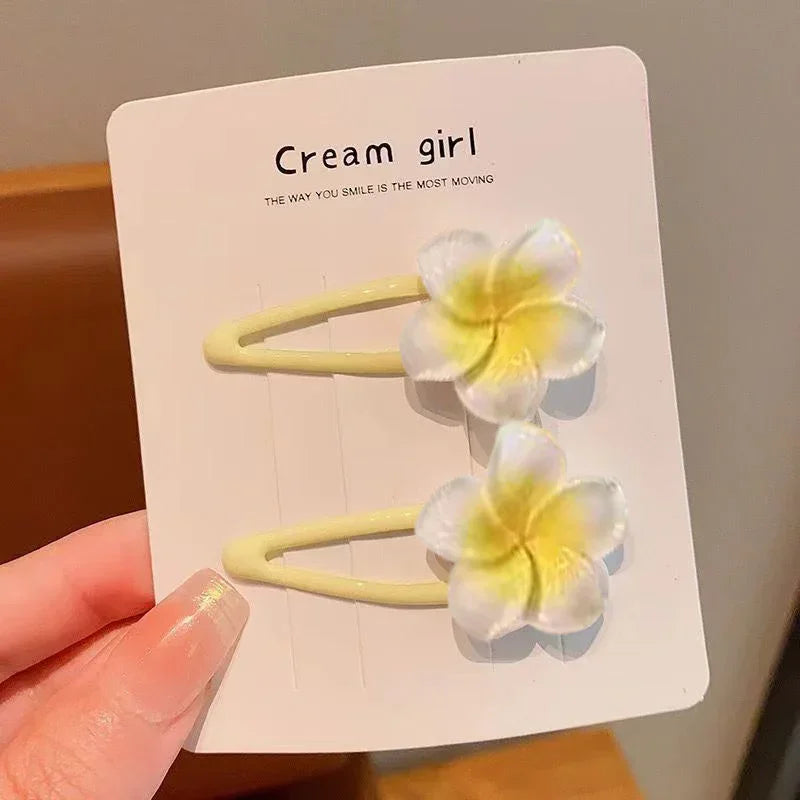Yellow hair clips with soft plastic plumeria flower accents, casual feminine accessory