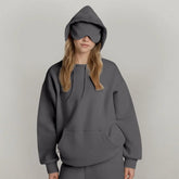 Woman in oversized gray hoodie and matching eye mask, relaxed fit, casual streetwear style
