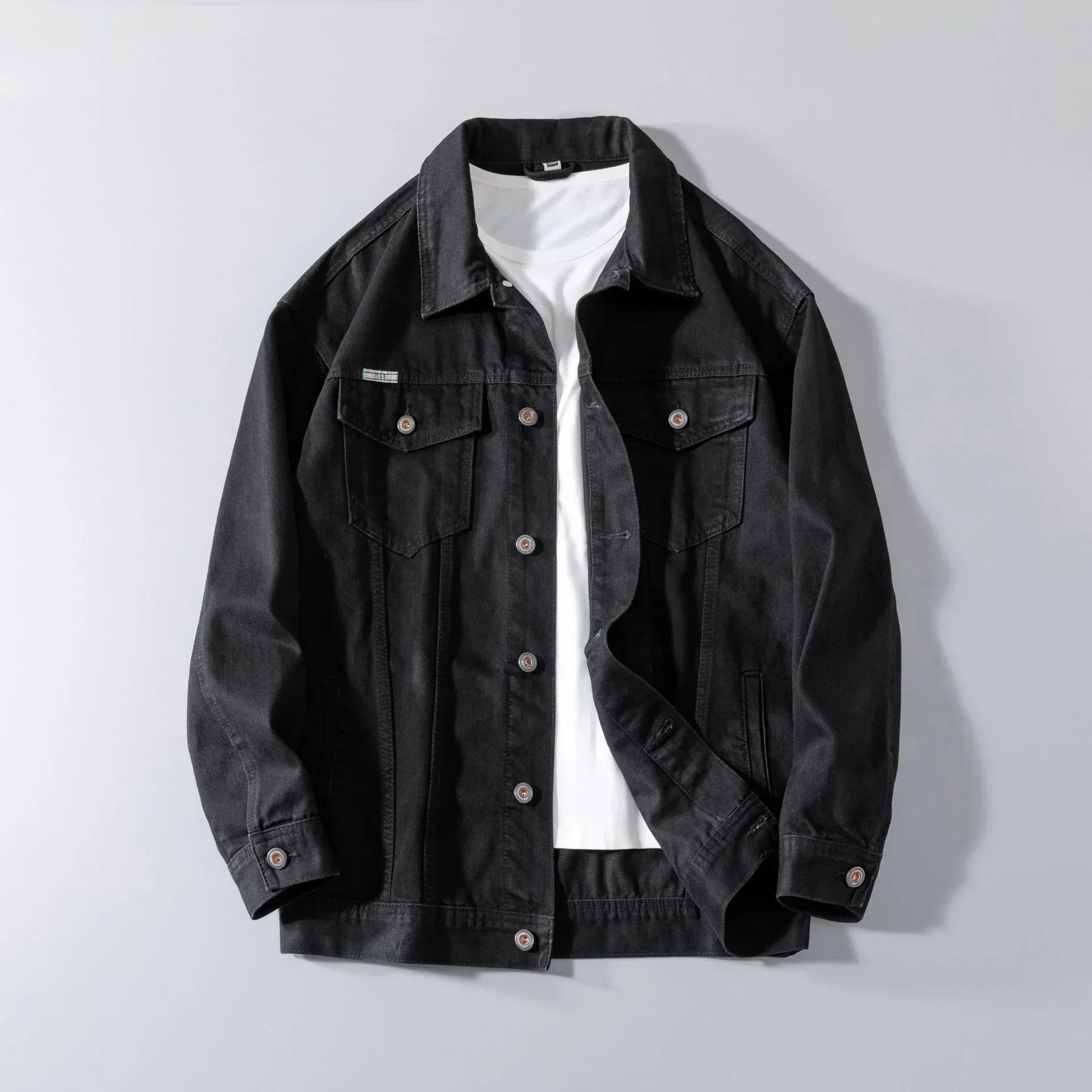 Black denim jacket with chest pockets layered over white t-shirt, relaxed fit streetwear style