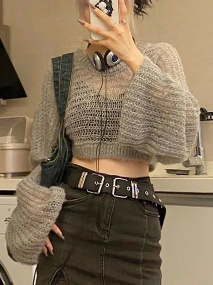 Woman wearing a loose-knit gray cropped sweater with balloon sleeves and a high-waisted black denim skirt