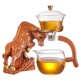 Bull-shaped ceramic tea set with glass teapot and cup containing herbal tea