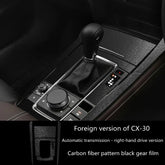 Carbon fiber pattern black gear shift cover for right-hand drive car, sleek modern interior.