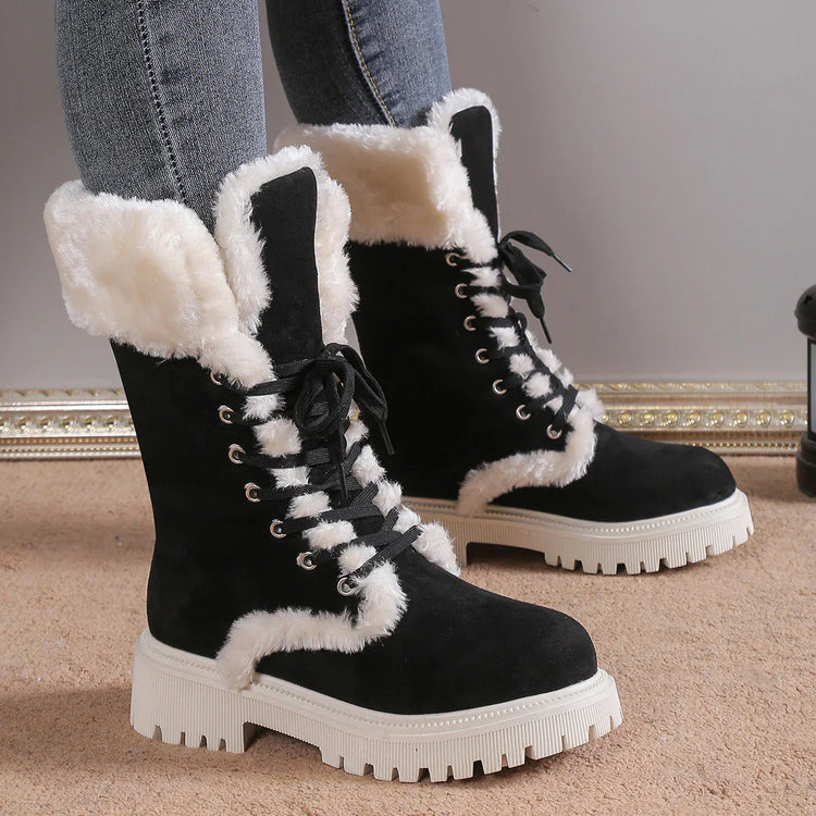 Black suede lace-up winter boots with white faux fur lining and chunky soles, worn with jeans