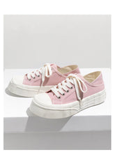 Pastel pink canvas sneakers with white rubber soles and laces, low-top casual style