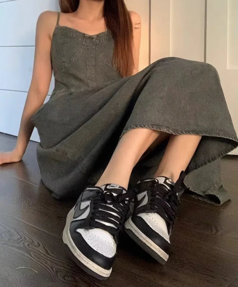 Woman wearing a grey denim maxi dress with a fitted bodice and black sneakers, casual style