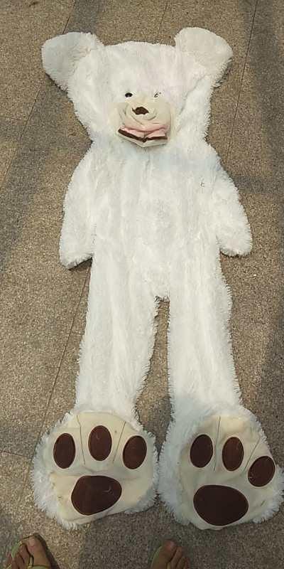 White faux fur bear costume with large paw feet and a loose, relaxed fit on tile floor