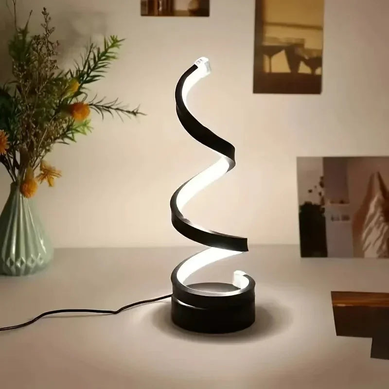 Modern spiral LED desk lamp with black and white finish on a minimalist table.